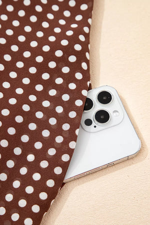 Brown polka dot maxi dress fabric detail with a white phone