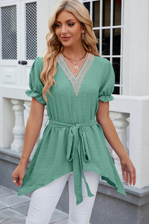 Green dotted swiss blouse with lace trim V-neck, short puff sleeves, belted waist, and asymmetric hem.