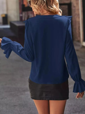 Dark blue blouse with cascading ruffle sleeves and button front detail.