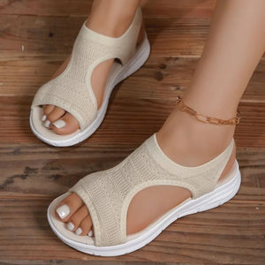 Beige knit sandals with white soles and cutouts, worn with an anklet.