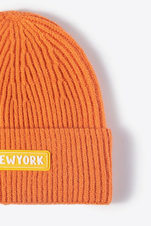 Orange ribbed acrylic beanie with a yellow New York patch detail.