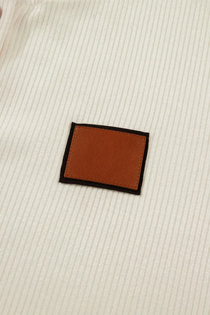 Cream ribbed knit maternity shirt with brown faux leather accent patch.