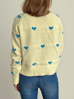 Pastel yellow knit sweater with blue heart pattern and ribbed trim.