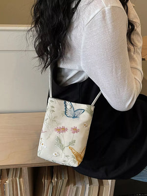 Delicate embroidered mini crossbody bag in off-white with butterfly and floral pattern.