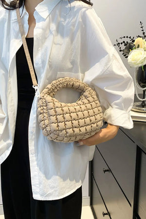 Padded crescent crossbody bag in khaki with sculptural texture and a ruched handle.