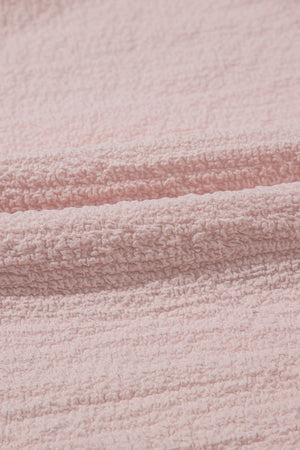 Blush pink textured blouse with ruffle sleeves and bow detail close-up