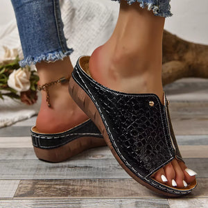 Black glossy crocodile-embossed wedge sandals with open toe and white stitching detail.