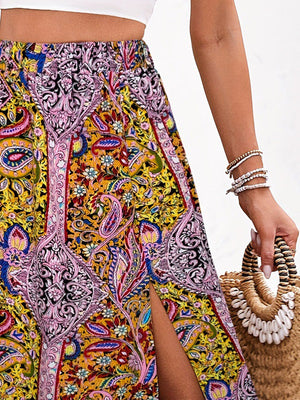 Maxi skirt with bold paisley print in yellow, pink, and blue, featuring a thigh-high slit.