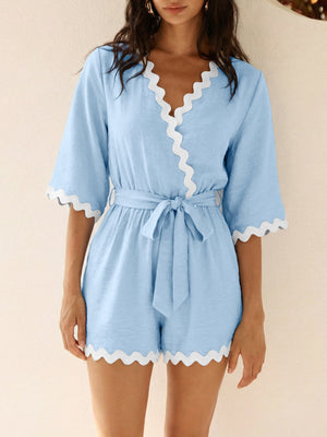 Blue maternity romper with 3/4 sleeves, V-neck, tie waist, and scalloped trim.