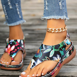 Embroidered floral thong wedge sandals with adjustable ankle strap and gold chain detail.