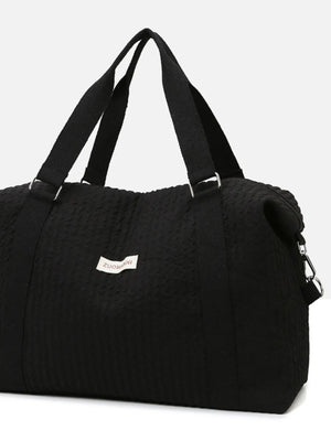 Black waffle-weave weekend bag with silver hardware and fabric handles