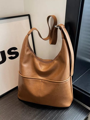 Brown leather hobo shoulder bag with adjustable strap and front pocket detail.