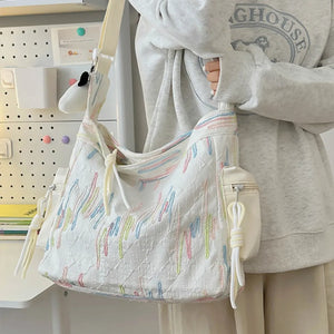 Ivory slouchy shoulder bag with quilted texture and colorful embroidered details.