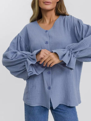 Light blue textured puff sleeve blouse with ruffled cuffs and button front.