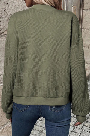 Textured quilted bomber jacket in sage green with a geometric pattern and ribbed cuffs.