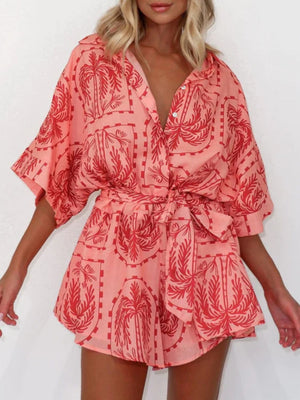 Wrap romper in strawberry with a celestial palm print, short sleeves, and tie waist.