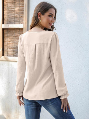 Beige textured pleat-front blouse with ruffle cuffs and long sleeves.