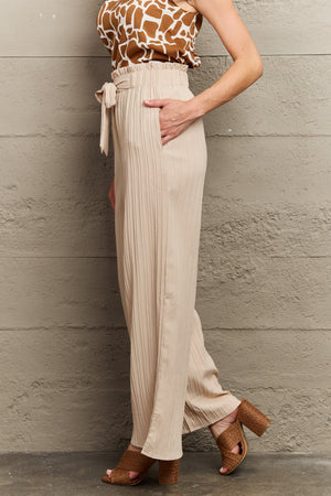 Pleated wide-leg trousers in apricot with paperbag waist and tie detail.
