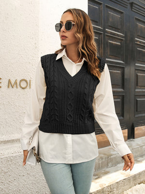 Black cable knit crop vest sweater with V-neck, worn over a white button-down shirt.