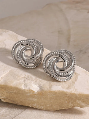 Silver swirl knot stud earrings with textured rope edge detail.