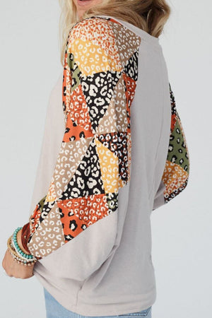 Patchwork raglan sleeve top in light gray with colorful leopard print panels on sleeves.