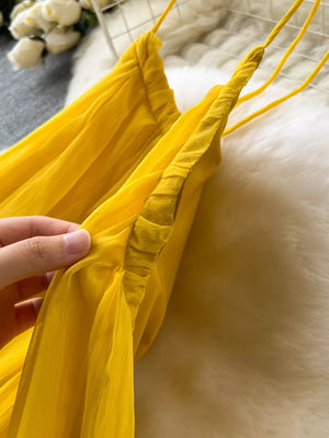 Yellow chiffon halter dress with ruched detail and thin spaghetti straps.