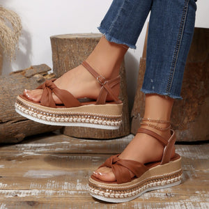 Brown bow knot wedge sandals with ankle buckle and braided trim detail.
