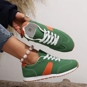 Green suede and canvas sneakers with orange stripe detail and white laces.