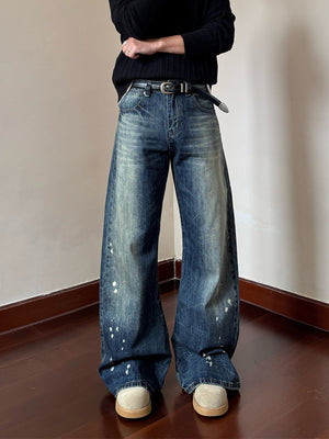 Men's vintage wash wide leg jeans in blue denim with paint splatters and a distressed look.