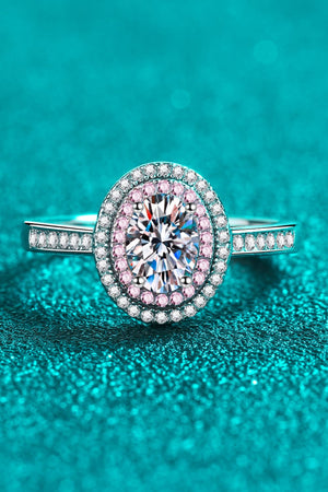 Silver oval halo ring with pink stone accents and a central diamond.