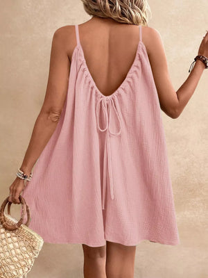 Dusty Pink spaghetti strap mini dress with back tie detail and textured fabric.