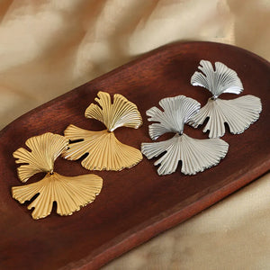Ginkgo leaf statement earrings in gold and silver with ribbed texture.