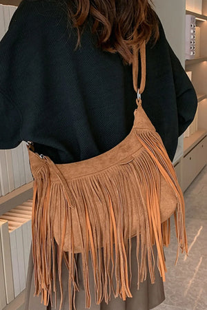Caramel suede crescent crossbody bag with long fringe detail.