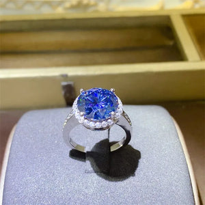 Silver halo cocktail ring with large blue sapphire and small clear stones.