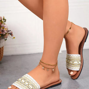 White embroidered artisan open-toe sandals with gold accents and moon charms.