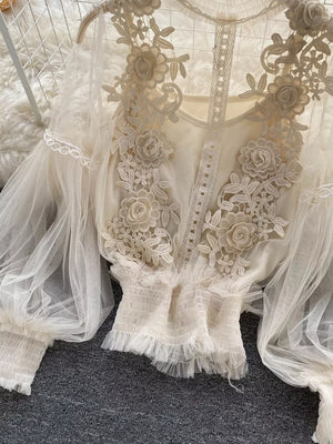 Creamy-white lace blouse with floral embroidery and sheer puff sleeves.