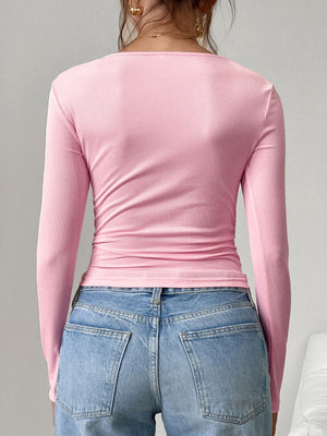 Pink ribbed square neck henley top with long sleeves, styled with jeans.