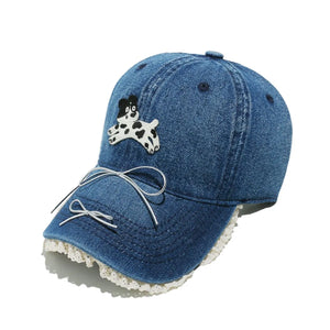 Denim baseball cap with puppy appliqué, lace trim, and bow detail.