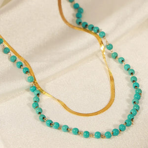 Gold layered necklace with turquoise beads and a snake chain.