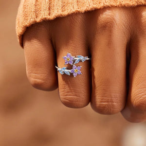 Silver bypass ring with purple and blue floral zirconia accents.