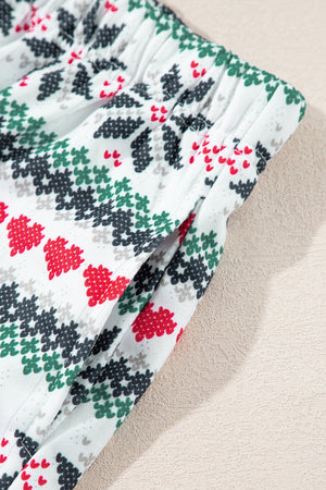 White cotton pajama shorts with a festive fair isle pattern of red hearts and green/black trees.