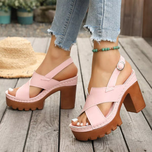 Pink open toe block heel sandals with cross straps and chunky sole.