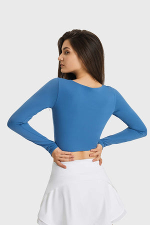 Blue long sleeve crop top with thumbhole sleeves and a keyhole neckline.