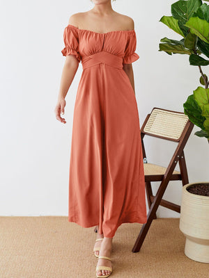 Coral off-the-shoulder jumpsuit with ruched waist detail and flutter sleeves.