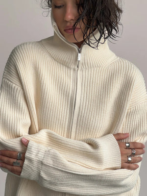 Cream ribbed knit zipper cardigan with a high neck and silver zipper detail