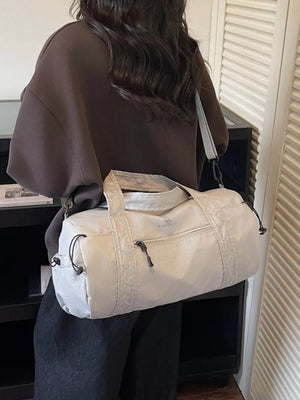 Light gray nylon travel bag with quilted details and zip pocket.