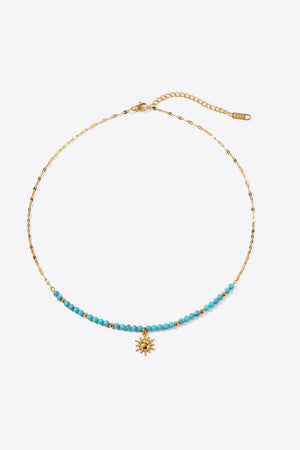Gold celestial sunburst beaded necklace with turquoise beads and gold chain.