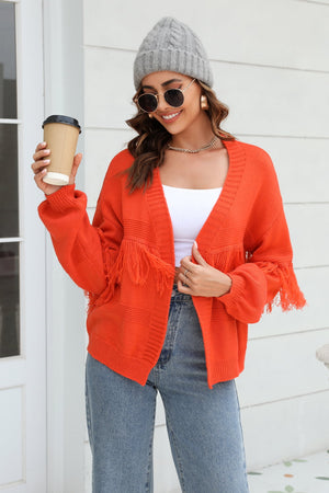 Orange acrylic cardigan with fringe detail on sleeves and hem.