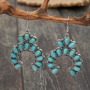 Turquoise crescent dangle earrings with teal stones and silver alloy metal.