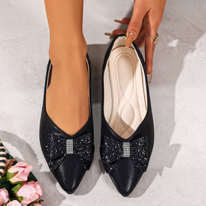 Black pointed toe flats with sparkly bow and rhinestone detail.